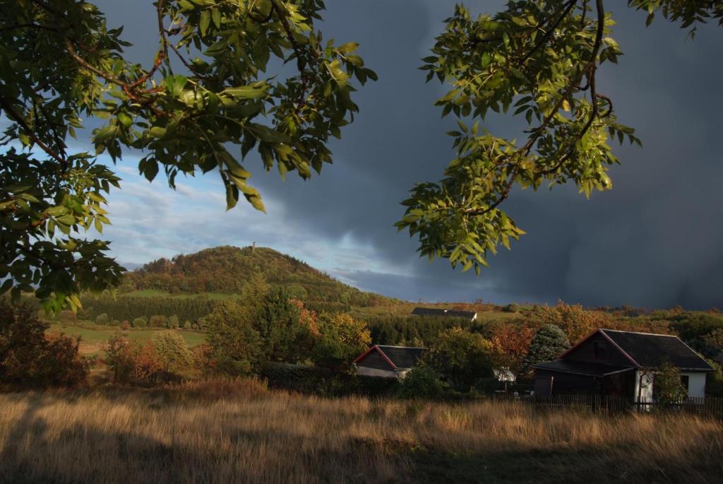 Bergkuppe und Wiesen unter dunklem Gewitterhimmel