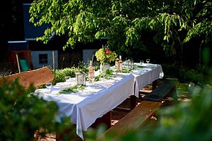 Gedeckte Tafel mit weißer Tischdecke im Garten
