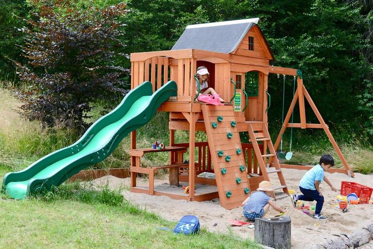 Spielplatz mit Rutsche, Kletterturm und Sandkasten im Garten