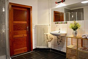 Badezimmer mit Waschbecken, Holztür und Heizkörper