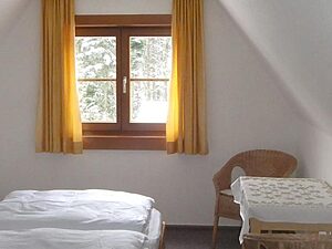 Schlafzimmer unter der Dachschräge mit Einzelbett und Korbsessel