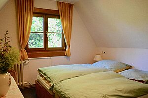 Schlafzimmer unter der Dachschräge mit grüner Bettwäsche